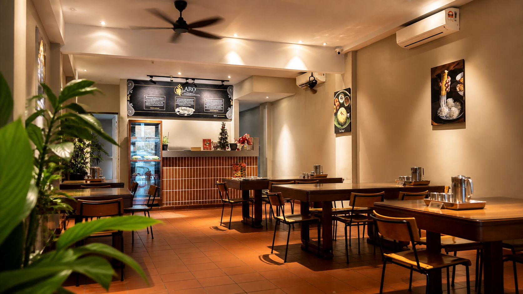Dining room at Aro Restaurant with wooden tables, chairs, ceiling fans and the service counter in view.